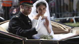 ARCHIV - Nach der Hochzeit fuhren Prinz Harry und seine Braut Meghan mit einer Kutsche an den jubelnden Fans vorbei. Foto: Aaron Chown/POOL PA/AP/dpa