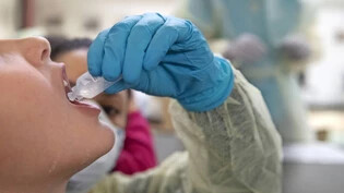 Das Bild wurde in Chiasso im Tessin aufgenommen: Schülerinnen und Schüler machen einen freiwilligen Coronatest und nehmen dazu für einige Sekunden eine Flüssigkeit in den Mund, die sie anschliessend in einen Speichelbehälter spucken.