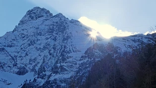 Naturspektakel im November: Die Sonne scheint bei schönem Wetter durch das Mürtschenloch auf das Dorf Mühlehorn.