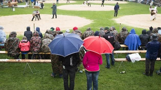 Besucher eines Schwingfests unter Regenschirmen