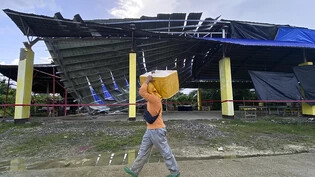Ein Fischverkäufer geht an einem eingestürzten Gebäude vorbei: Vor der Küste der Insel Mindanao hat sich ein starkes Erdbeben ereignet. Tsunami-Wellen drohten im Anschluss. Foto: Ivy Marie Mangadlao/AP