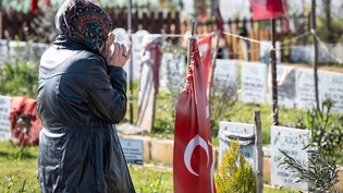 Eine Frau betet am Grab ihrer beim Erdbeben getöteten Familienmitglieder auf einem Gräberfeld am Rande von Adiyaman in der Türkei. Kurz vor dem ersten Jahrestag der Erdbebenkatastrophe kommen hunderte Angehörige zu den Gräbern ihrer Angehörigen, die bei…