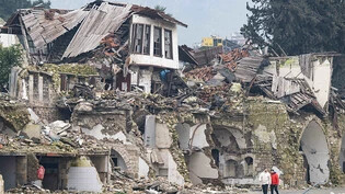 dpatopbilder - Zwei Männer gehen an einer völlig zerstörten Häuserzeile in der Provinz Hatay vorbei. Im Zentrum der Stadt waren bei dem Beben vor einem Jahr unzählige Häuser zerstört oder beschädigt worden. Foto: Boris Roessler/dpa