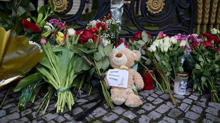 Blumen und ein Teddybär liegen am Zaun der russischen Botschaft in Berlin. Foto: Jörg Carstensen/dpa