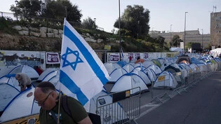 Mit einer israelischen Flagge in der Hand geht ein Mann an einem von Regierungsgegnern errichtetem Zeltlager in der Nähe der Knesset, dem israelischen Parlament, vorbei. Foto: Leo Correa/AP