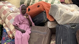 PRODUKTION - Eine junge Frau aus dem Sudan sitzt im Transitlager inmitten von Koffern, dem Hab und Gut der Flüchtlinge. Die Menschenrechtsorganisation Amnesty International hat ein Jahr nach Beginn des Konflikts im Sudan eine Kampagne für ein…
