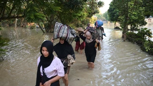 dpatopbilder - Menschen tragen ihre Habseligkeiten, während sie durch das Wasser in einem überfluteten Dorf waten. Foto: Reza Saifullah/AP/dpa