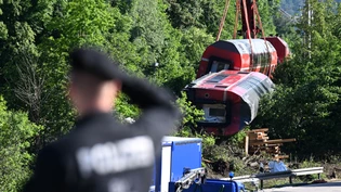 ARCHIV - Ein Polizist betrachtet aus der Ferne den Unfallort, wo zwei Waggons noch geborgen werden müssen. Foto: Angelika Warmuth/dpa