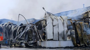dpatopbilder - Ein Feuerwehrmann versprüht Wasser nach einer Explosion und einem Brand in einer Keksfabrik in Trikala. Foto: George Kidonas/InTime News/AP/dpa