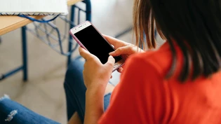 Bündelt Aufmerksamkeit: Ein Mädchen hängt kurz vor Unterrichtsbeginn am Smartphone.