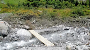 Ausgefranste Uferpartie: Die rote Markierung auf dem Stein links zeigt, wie hoch über dem Bach die weggeschwemmte Brücke stand. 