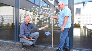 Mario Beretta (links) und Peter Jud, Leiter der Hauswarte Schulhäuser, diskutieren die Höhe der aufgeklebten Schmetterlinge.