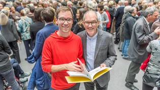 Andrea Meuli (rechts) übergibt die Buchpublikation an Chris Hunter.