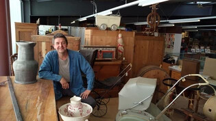 Tobias Häberli sitzt an seinem Brocki-Lieblingsobjekt, einem massiven Holztisch.