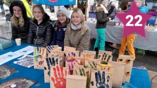 Gemeinsam auf dem Weihnachtsmarkt: Schülerinnen verkaufen an einem Stand selbst bedruckte Papiertüten mit Reis – für einen guten Zweck.